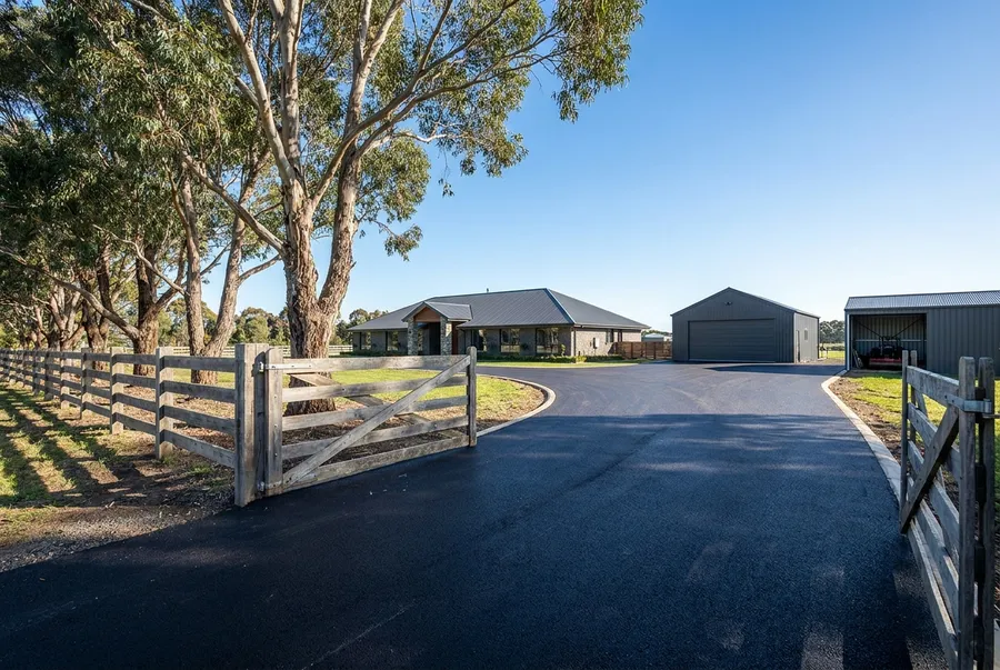 Long new asphalt driveway to a country homestead and shed