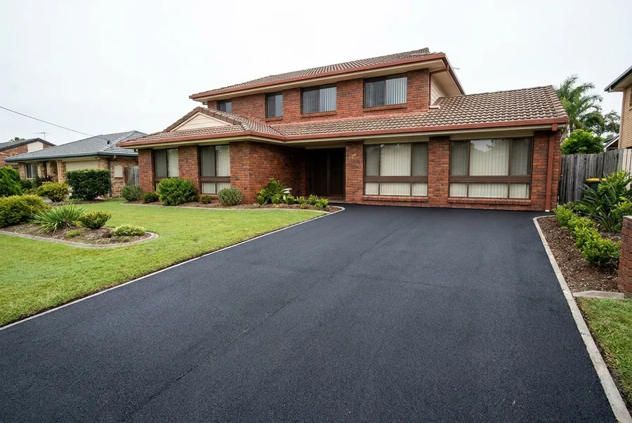 New asphalt double driveway at a red brick home