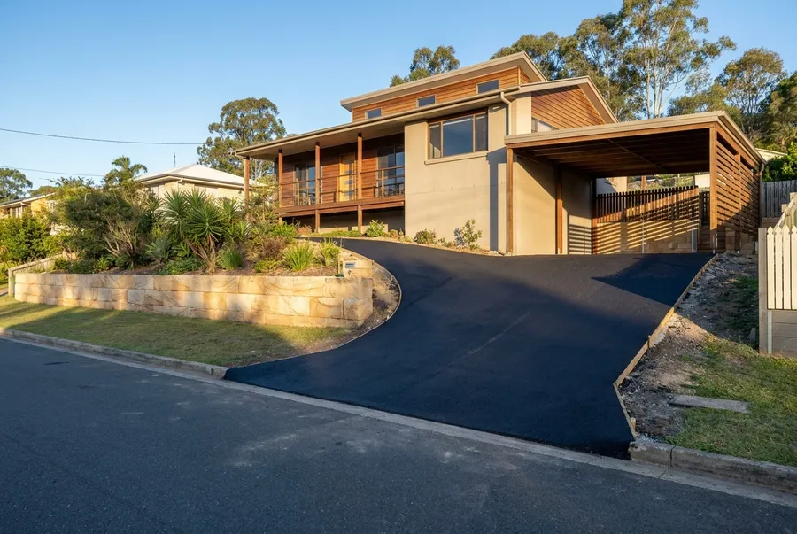 New asphalt driveway rising steeply to a highset home